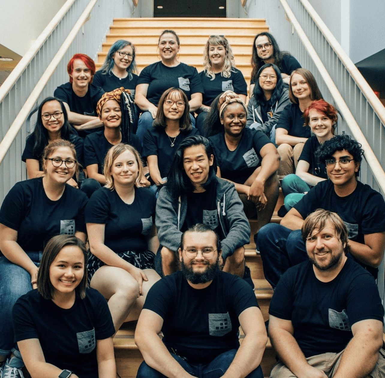 A group photo of Amy with a large team, all wearing matching dark t-shirts